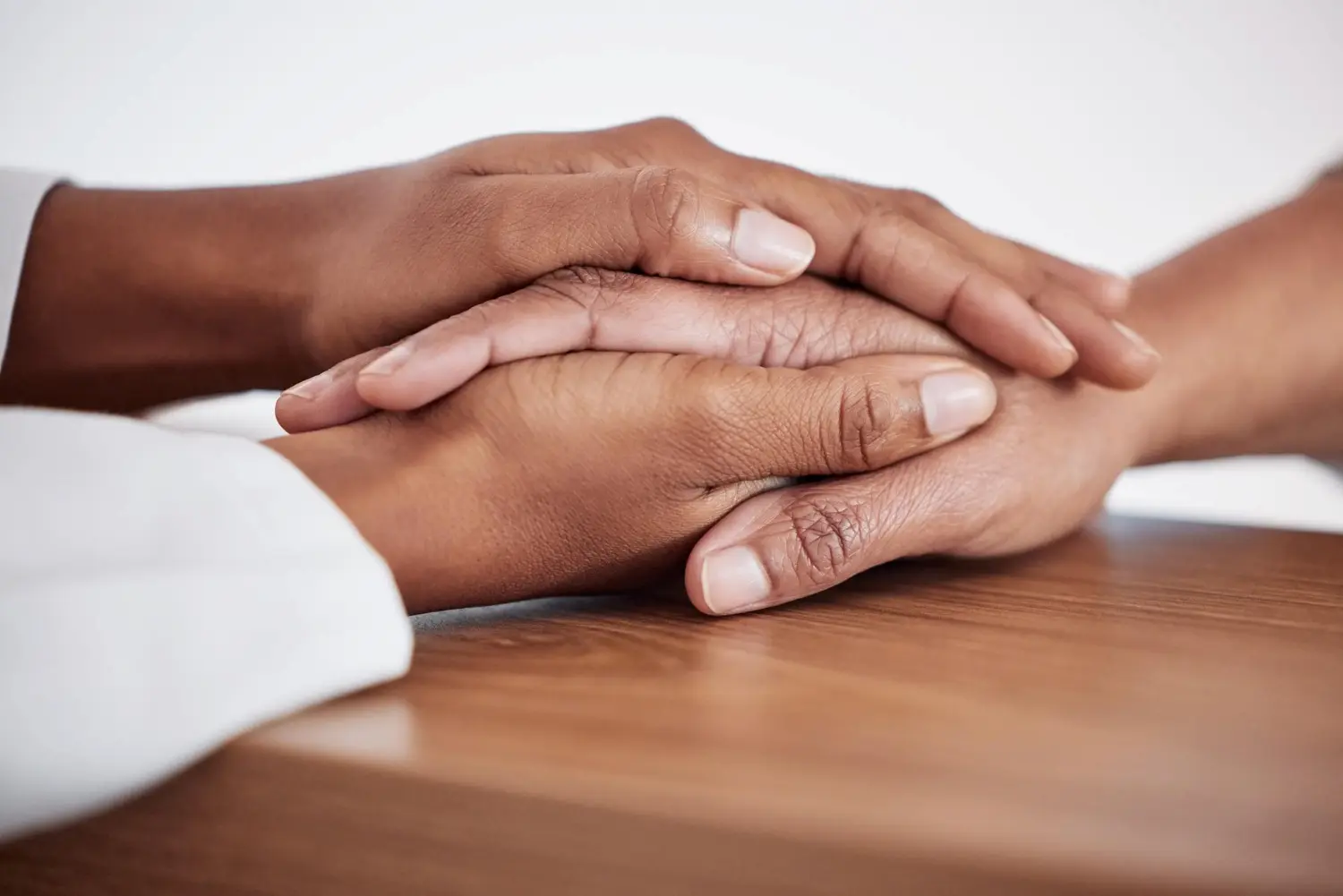 Two people's hands resting together in a quiet gesture of comfort and support
